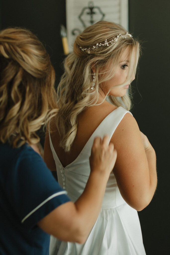 a mother helps her daughter into her wedding dress