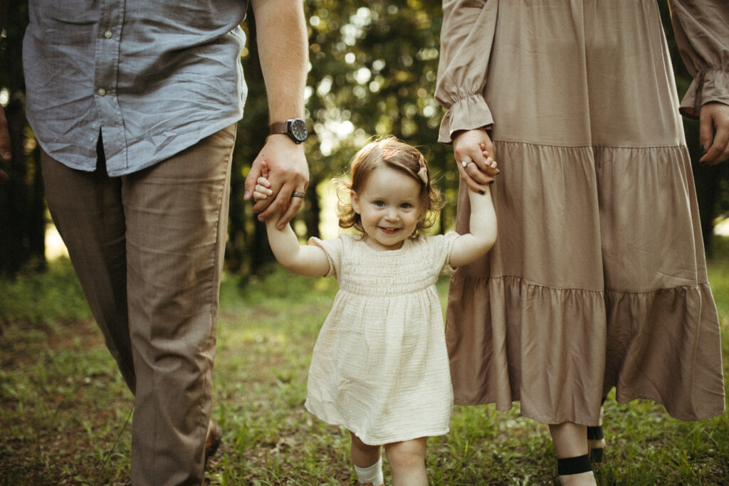 A family walks hand in hand towards the photographer. 