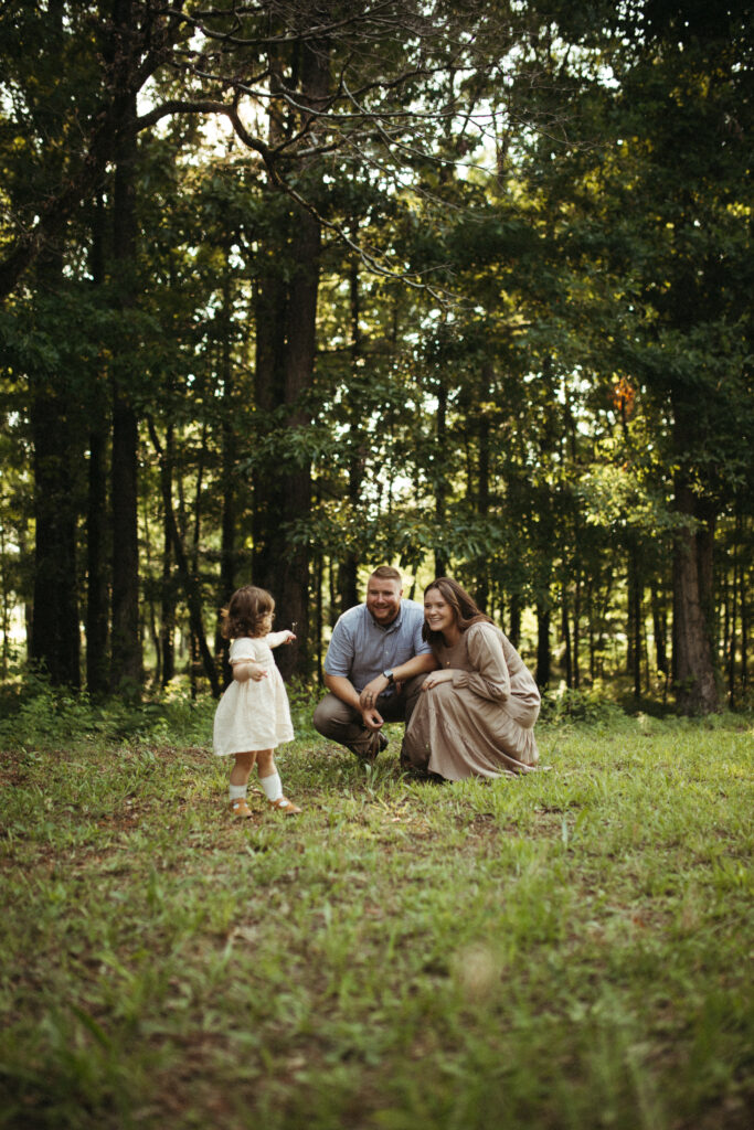 a mom and dad engage with their daughter showing them a flower she found 