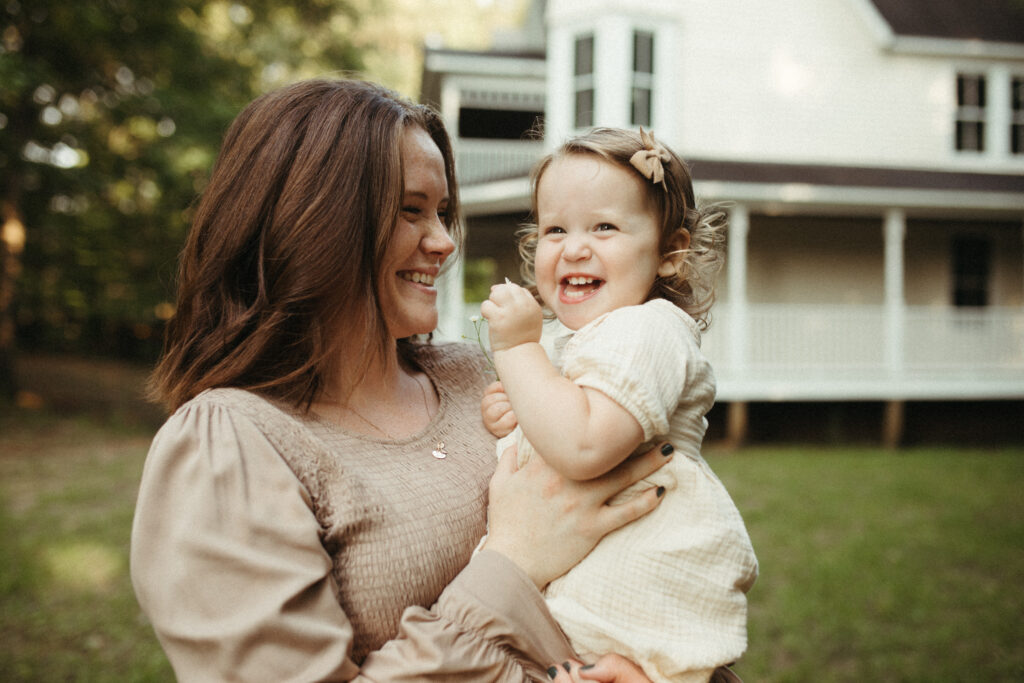 mom and daughter giggling at dad behind the photographer