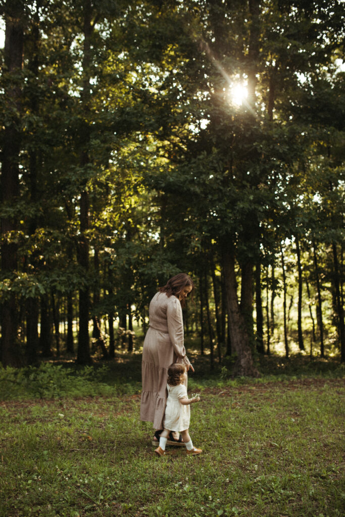 mom and daughter walk hand in hand in the golden rays of summer