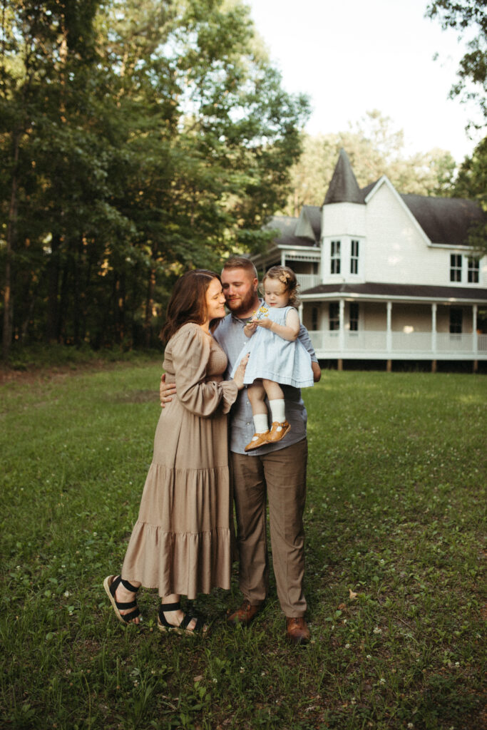 Dad looks on at mom with love as she looks at her daughter with flowers and joy