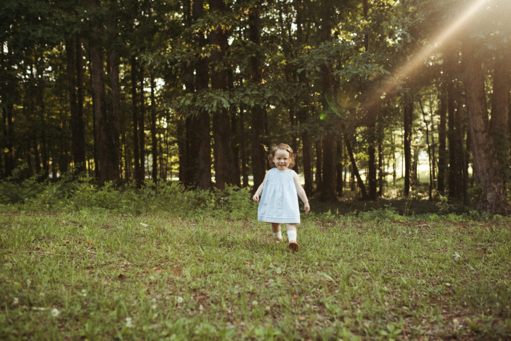 a daughter giggles at her parents behind the photographer while basking in the golden rays of summer